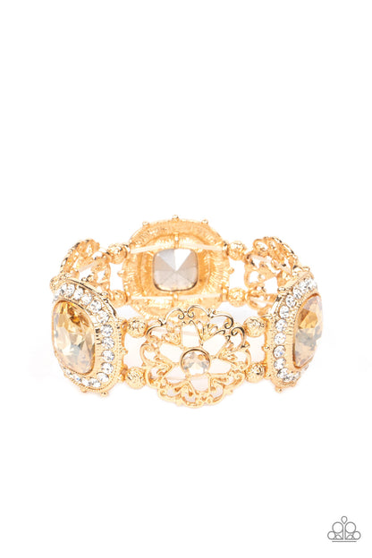 Gilded Gallery Gold Bracelet - Paparazzi Accessories   Oversized faceted golden gems in dramatically rounded square cuts are wrapped in borders of classic white rhinestones, emitting a breathtaking sheen. Floral-inspired frames, dotted with solitaire golden rhinestones, bloom in between the large rhinestones, adding airy accents to the bold design, as textured gold beads separate each frame as they're threaded along stretchy elastic bands.  Sold as one individual bracelet.  December 2022 Life of the Party!