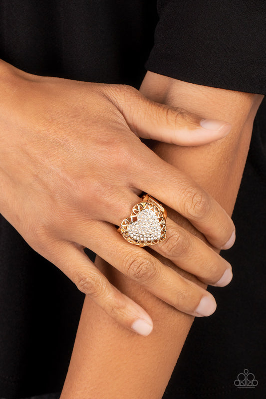 Romantic Escape Gold Ring - Paparazzi Accessories  An airy gold frame with cutouts resembling a subtle zig-zag pattern, wraps around a heart filled with brilliant white rhinestones to create a dazzling centerpiece atop the finger. Features a stretchy band for a flexible fit.  Sold as one individual ring.