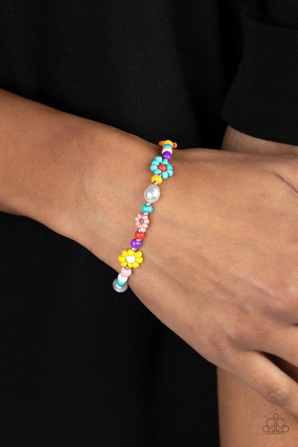 Modeled after gerber daisies, multicolored seed beed petals in shades of Tiffany, orange, pink, and yellow bloom around white, red, and silver beaded centers resulting in a dazzling collection of florals around the wrist. Varying sizes of beads in the same shades, along with a couple of small baroque pearls, separate the floral designs in a far-out finish. Features an adjustable clasp closure.  Sold as one individual bracelet.