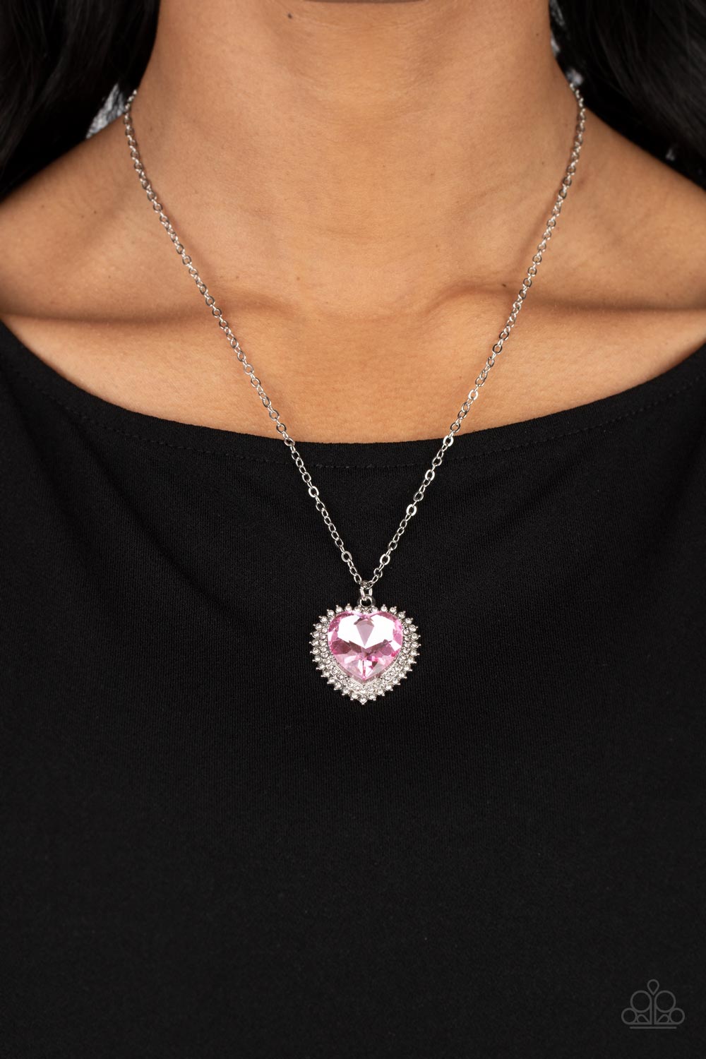 Sweethearts Stroll Pink Necklace - Paparazzi Accessories  A pink crystal-like heart gem sparkles dramatically as it's wrapped in a glassy white rhinestone-studded heart frame. Adding additional shimmer, a second layer of white rhinestones encircles the studded pendant as it swings from a classic silver chain in a flirty finish. Features an adjustable clasp closure.  Sold as one individual necklace. Includes one pair of matching earrings.