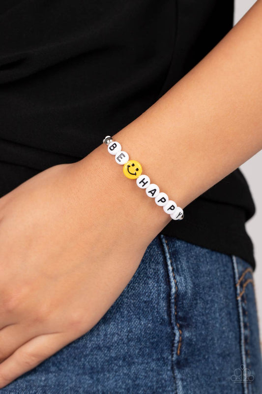 I Love Your Smile White Bracelet - Paparazzi Accessories  Strung along a white string, white beads are stamped with black letters that make out the phrase "Be Happy." A yellow bead with a smiley face separates the words "be" and "happy" for a cheery pop of color. Silver beads border the cheery beads, grounding the design to the beads hanging at the end of the adjustable sliding closure that wraps around the wrist. Features an adjustable sliding knot closure.  Sold as one individual bracelet.