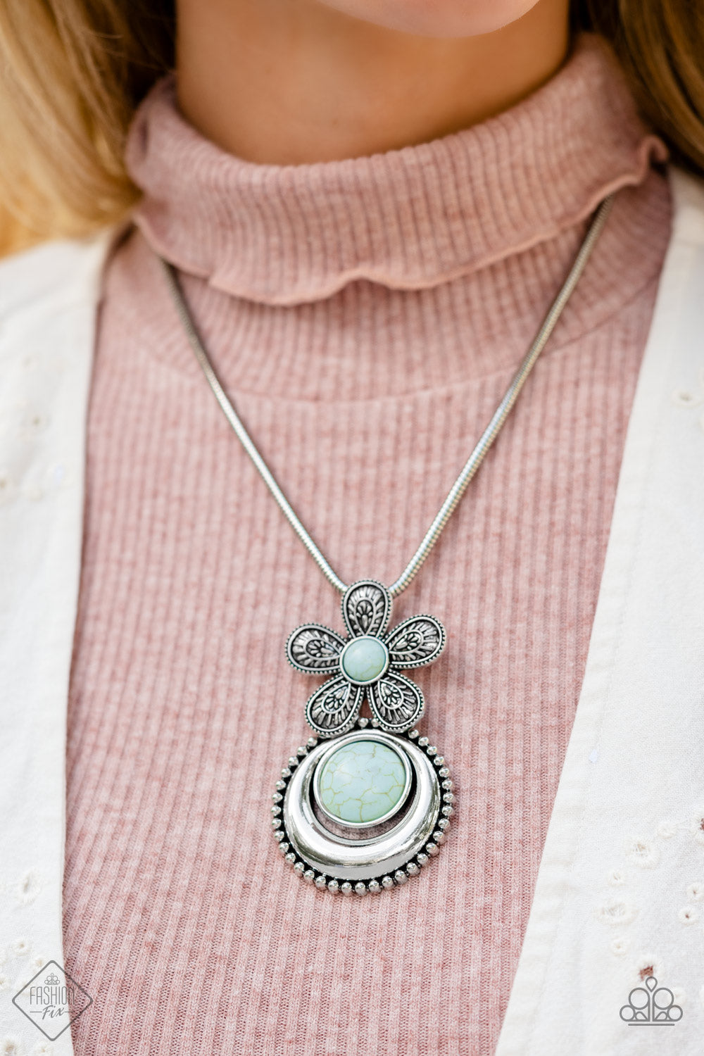 Fluttering from a silver snake chain, an oversized flower with detailed petals blooms around a light blue stone center. A silver pendant with a studded border swings from the single flower for additional movement. A refreshing oversized stone in the same hue is pressed into the center of the pendant for a pop of color amongst the metallic texture. Features an adjustable clasp closure. As the stone elements in this piece are natural, some color variation is normal.