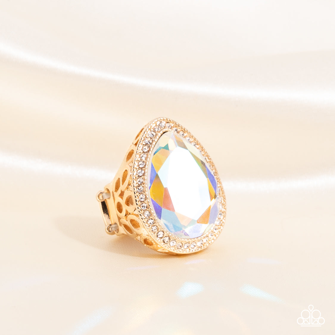 Illuminated Icon Gold Ring - Paparazzi Accessories  An oversized teardrop gem with an iridescent finish is nestled inside a gold teardrop frame encrusted in dainty white rhinestones. Airy teardrop cutouts decorate each side of the oversized frame### some with subtle texture and others with a high sheen finish. Features a stretchy band for a flexible fit. Due to its prismatic palette### color may vary.  Sold as one individual ring.