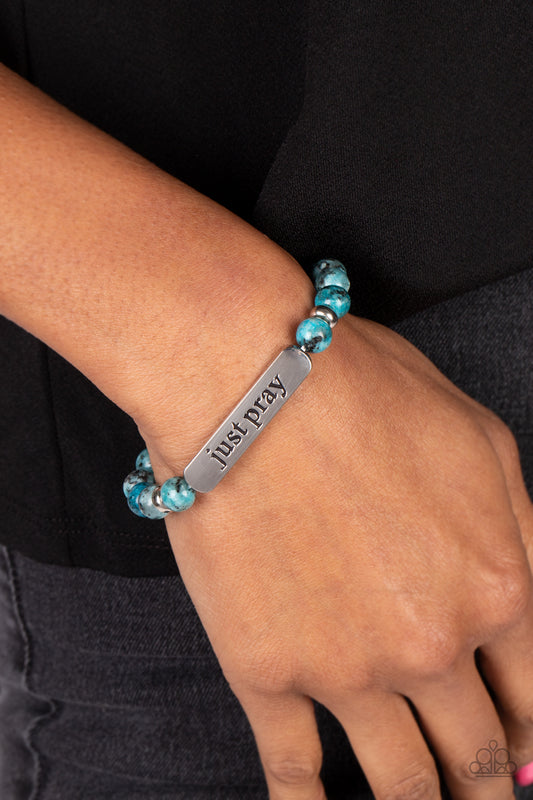 Just Pray Blue Stretch Bracelet - Paparazzi Accessories  Smooth, light blue speckled stones are stretched across the wrist on an elastic stretchy band, with accents of silver beads sprinkled in. Meeting in the center of the stony display, a curved rectangular bar is stamped with the phrase "just pray" for an inspiring finish. As the stone elements in this piece are natural, some color variation is normal.  Sold as one individual bracelet.