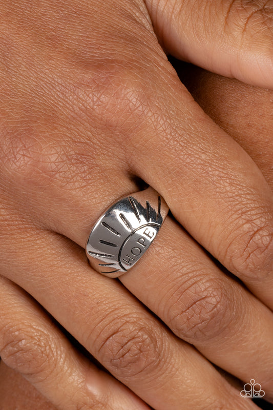 Hope Rising Silver Ring - Paparazzi Accessories  A band of high-sheen silver curves around the finger, creating a half-circle. The word, "HOPE" is etched along the bottom edge of the half-circle, where it is nestled inside the outline of a sun. Linear etchings fan out across the silver backdrop, radiating energetically from the empowering message below. Features a dainty stretchy band for a flexible fit.  Sold as one individual ring.