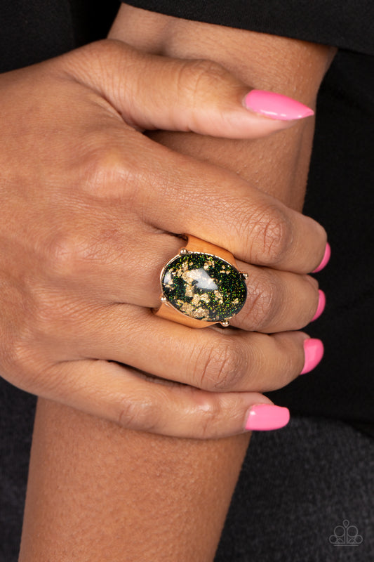 Gold Leaf Glam Black Ring - Paparazzi Accessories  Encased in a sleek gold frame, an oversized glassy black bead with an opalescent finish, is speckled in flecks of gold shimmer for a bubbly, yet glitzy effect. Thick, sleek, gold curves from the glassy bead, anchoring the oversized shimmer to the design. Features a stretchy band for a flexible fit.  Sold as one individual ring.