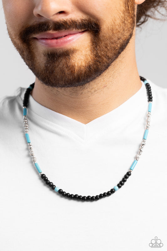 Volcanic Valiance Blue Unisex Necklace - Paparazzi Accessories  Black wooden beads, striped silver beads, silver studs, turquoise cylindrical stones, and turquoise round stones are threaded along an invisible wire, creating an urban pop of color below the collar. Features an adjustable clasp closure. As the stone elements in this piece are natural, some color variation is normal.  Sold as one individual necklace.  Sku:  P2SE-URBL-065XX