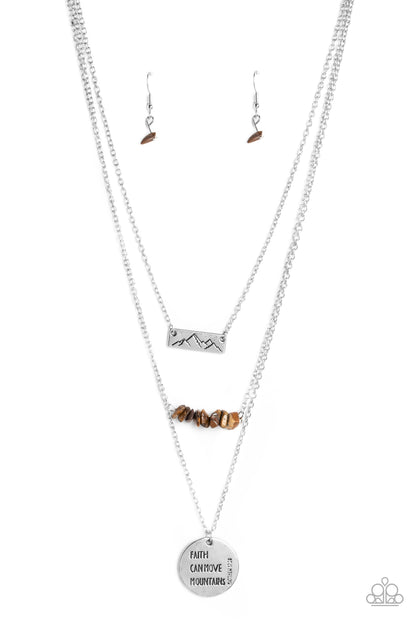 Miracle Mountains Brown Necklace - Paparazzi Accessories  Infused with three earthy pendants, three shimmery silver chains layer across the chest. A silver rectangular plate, stamped with a mountain outline swings from the uppermost chain above a row of chiseled tiger's eye stones. An oversized shimmery silver disc stamped with the phrase "Faith can move mountains" with the scripture reference "Matthew 17:20" listed to the side of the disc hangs from the lowermost chain for a wanderlust vibe.