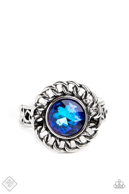 Round Table Runway Blue Ring - Paparazzi Accessories  High-sheen silver chain links encircle a vibrant, faceted blue gem center, creating a gorgeous contrast of grit and glam. A band of silver chain link arcs across the finger underneath the colorful centerpiece, resulting in an edgy centerpiece that sits boldly atop the finger. Features a dainty stretchy band for a flexible fit.  Sold as one individual ring.