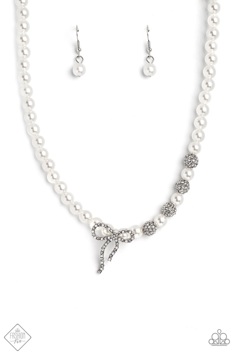 Classy Cadenza White Pearl Necklace - Paparazzi Accessories  A strand of classic white pearls coalesces down the neckline in a feminine display. Airy silver spheres, adorned in sparkling white rhinestones, are effortlessly sprinkled among the sea of pearls on one side, infusing the design with capricious shimmer. Then in the perfect finishing touch, a ribbon of silver, adorned in tiny white pearls and sparkling white rhinestones, loops into a bow at the bottom of the design.