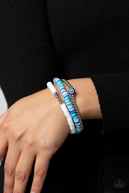 EYE Have A Dream Blue Bracelet - Paparazzi Accessories  Varying in multicolored shades, hues of blue and white rubber discs pair with shiny silver beads and silver accents creating colorful layers across the wrist. Featured on the silver-beaded bracelet, a glassy bead with an eye-like design contributes an additional shade of blue to the fashionable design.  Sold as one set of three bracelets.  P9SE-BLMT-430XX