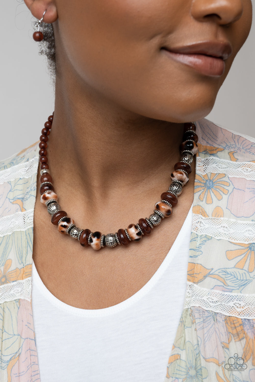 Warped Whimsicality Brown Necklace - Paparazzi Accessories  An earthy collection of dotted silver beads, rounded milky Caramel Café beads, studded silver rings, brown-spotted ceramic-like beads and textured silver beads are threaded along an invisible wire below the collar for an authentic artisan flair. Features an adjustable clasp closure.  Sold as one individual necklace. Includes one pair of matching earrings.  P2ST-BNXX-081LN