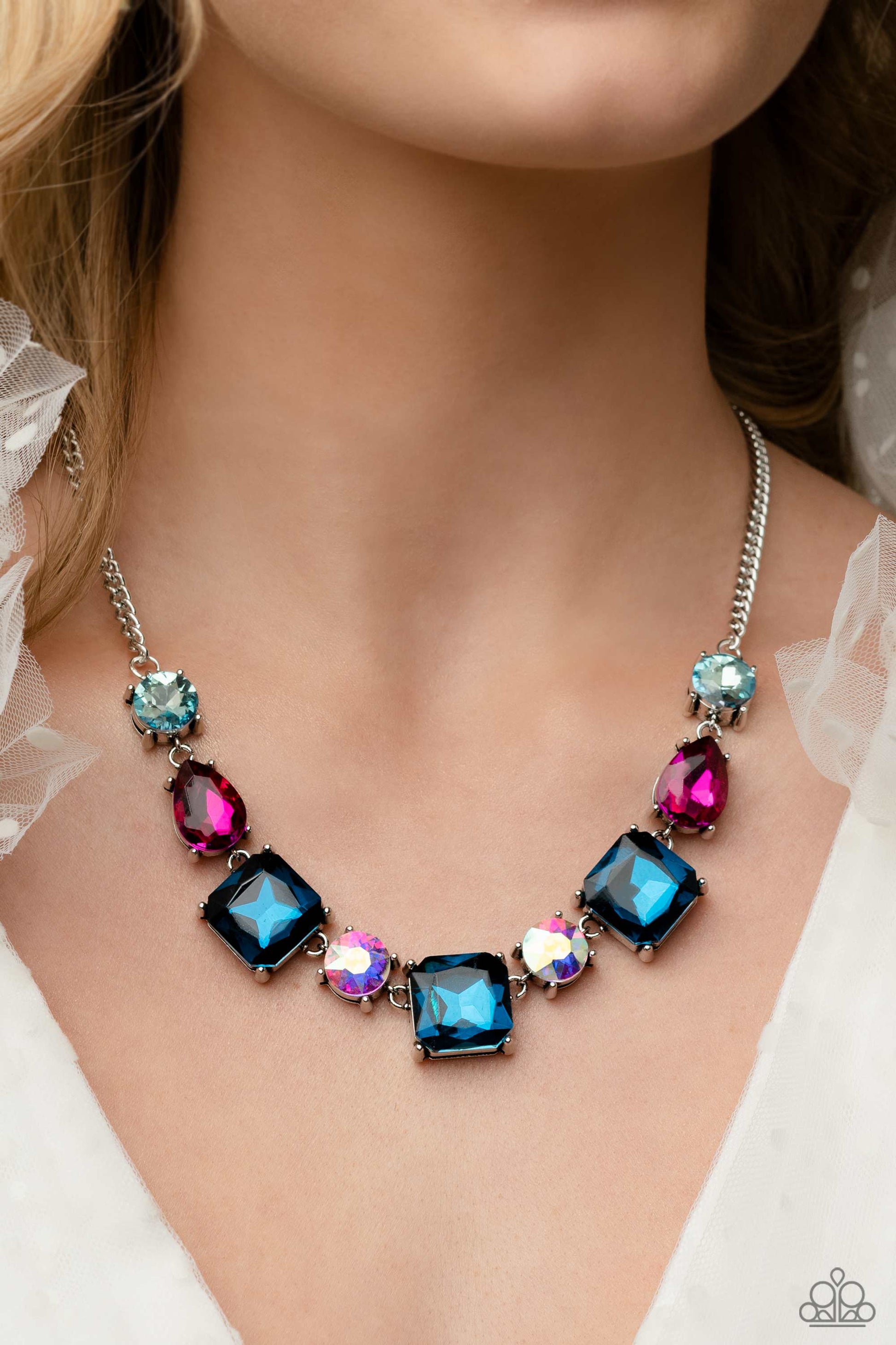 ﻿Elevated Edge Multi Necklace - Paparazzi Accessories  Encased within thick, pronged, elevated silver settings, a geometric collection of fuchsia, light blue, dark blue, and iridescent rhinestones, featured in square, teardrop, and round shapes coalesces down the neckline for a gritty, yet glamorous display. Features an adjustable clasp closure. Due to its prismatic palette, color may vary.  Sold as one individual necklace. Includes one pair of matching earrings.  P2RE-MTXX-215XX