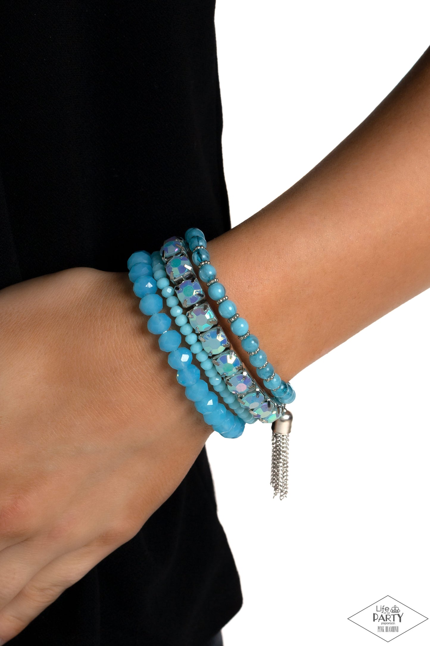 Day Trip Trinket Blue Stretch Bracelet - Paparazzi Accessories  Pinched in silver fittings, a band of UV shimmery Waterspout beads joins mismatched strands of smoky, glassy, and faceted blue beads creating four stretchy bracelets around the wrist. A single silver chain tassel dances from the crystalline compilation for a final flirty finesse.  Sold as one set of four bracelets.  P9WH-BLXX-283XX