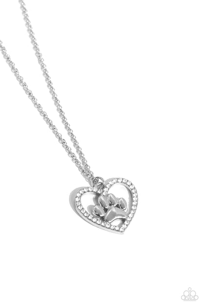 PET in Motion White Paw Print Necklace - Paparazzi Accessories  Featuring a paw print charm, an airy rhinestone-embossed heart frame glides down the neckline on a dainty, classic silver chain for a pet-lover inspired pendant. Features an adjustable clasp closure.  Sold as one individual necklace. Includes one pair of matching earrings.  P2DA-WTXX-271XX