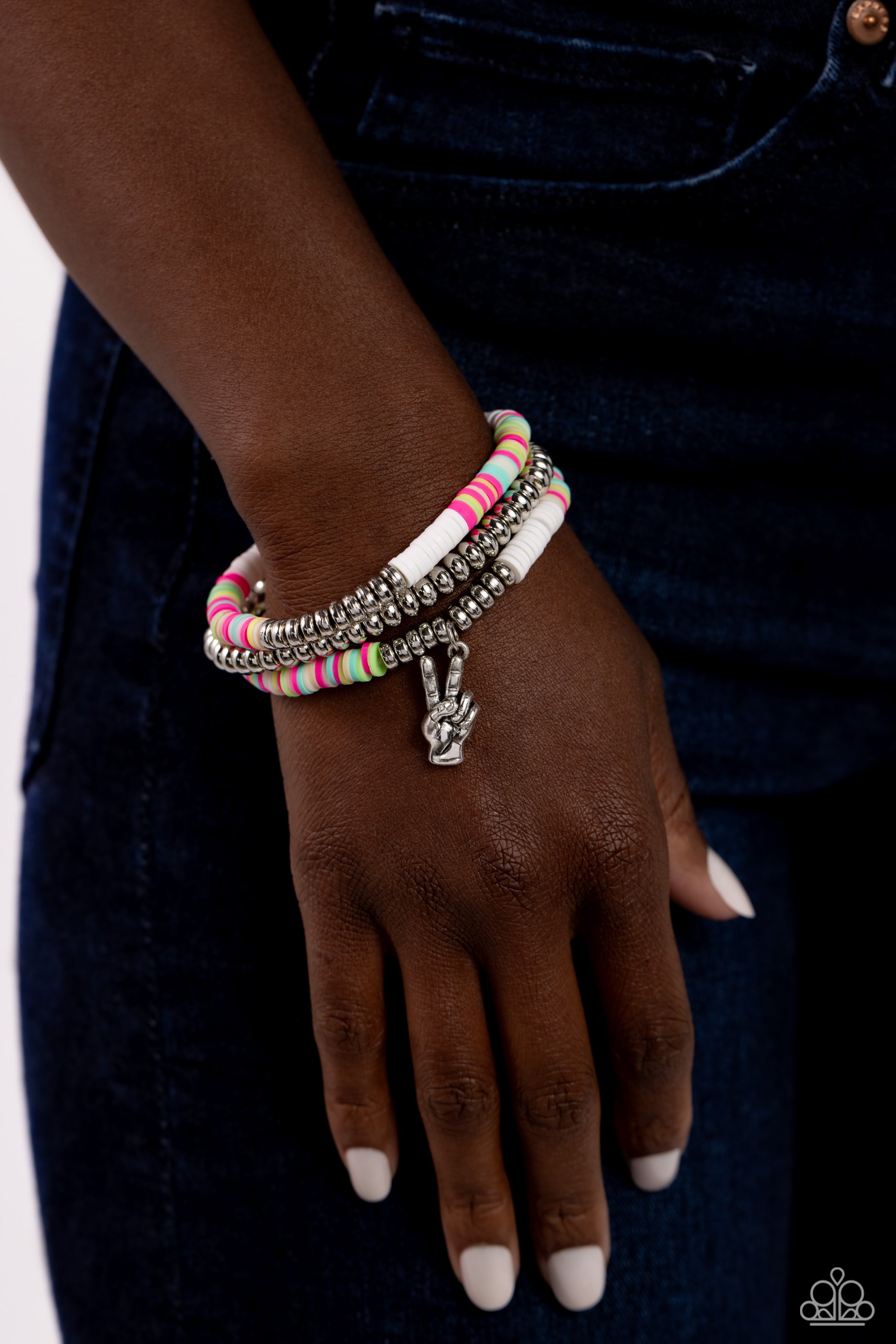 Peaceful Potential White Stretch Bracelet - Paparazzi Accessories  Infused along stretchy bands white, pink, green, blue, and tan rubber discs combine with sporadically placed silver discs and a silver disc strand for a vibrant pop of color along the wrist. A silver peace sign dangles from one of the colorful strands for a youthful finish.  Sold as one set of three bracelets.  P9WH-WTXX-260XX
