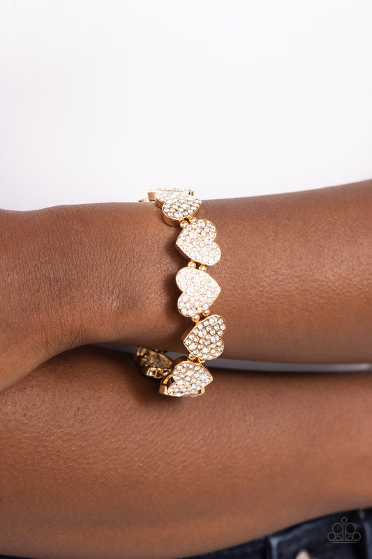 Headliner Heart Gold Stretch Bracelet - Paparazzi Accessories  Dotted with various sizes of dainty white rhinestones, sleek gold hearts alternating in direction link together around the wrist along a stretchy band for a flirtatious finish.  Sold as one individual bracelet.  SKU: P9RE-GDXX-407XX