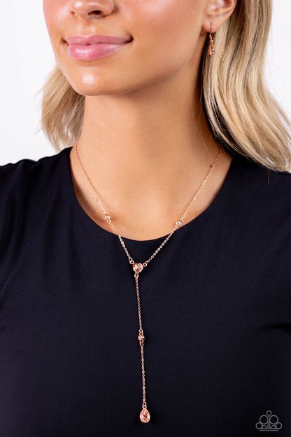 Lavish Lariat Shiny Copper Necklace - Paparazzi Accessories  Dainty strands of glistening shiny copper chain delicately knot into a timeless tassel for a refined flair. Peachy gems in varying sizes and in round, teardrop, and heart applications are infused along the shiny copper chain in sleek shiny copper fittings for a touch of light-reflecting dazzle. Features an adjustable clasp closure.  Sold as one individual necklace. Includes one pair of matching earrings.  New Kit Sku:  P2RE-CPSH-226XX