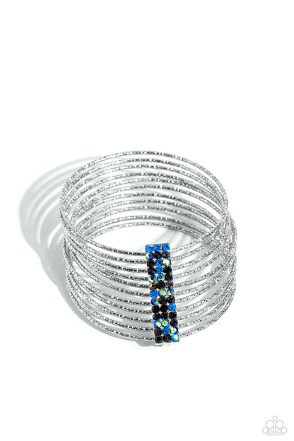 Shimmery Silhouette Multi Rhinestone Bangle Bracelet - Paparazzi Accessories  Held together by an elongated rectangular silver fitting and encrusted in three rows of Montana, hematite, black, blue, and blue iridescent gems, silver bangles embossed in shimmery diamond-cut textures stack across the wrist for a refined display. Due to its prismatic palette, color may vary.  Sold as one individual bracelet.  SKU: P9RE-MTXX-143XX