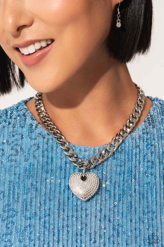 Ardent Affection White Heart Necklace - Paparazzi Accessories  Featuring an intense white rhinestone embellishment, an oversized silver heart frame swings from the bottom of a thick silver curb chain for an edgy declaration. Features an adjustable clasp closure.  Sold as one individual necklace. Includes one pair of matching earrings.  SKU: P2ST-WTXX-138XX  *LOP January 2024
