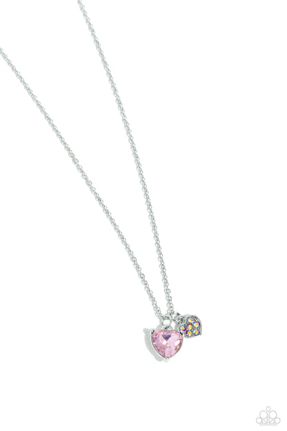 Devoted Delicacy Pink Heart Necklace - Paparazzi Accessories  Gliding along a dainty silver chain, a light pink gem heart, set in pronged fittings, stands out against the neckline. A smaller pink iridescent-embossed silver heart lays next to the gem heart for additional eye-catching color. Features a stretchy band for a flexible fit. Due to its prismatic palette, color may vary.  Sold as one individual necklace. Includes one pair of matching earrings.  SKU: P2DA-PKXX-195XX