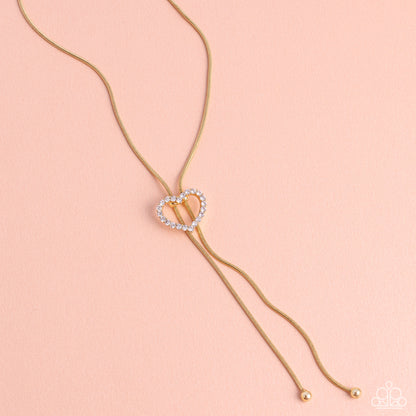 Tempting Tassel Gold Heart Bolo Necklace - Paparazzi Accessories  A dainty white rhinestone-encrusted heart silhouette slides along dainty strands of glistening gold snake chain for a timeless, refined tassel. Features a bolo closure.  Sold as one individual necklace. Includes one pair of matching earrings.  Sku:  P2DA-GDXX-327XX