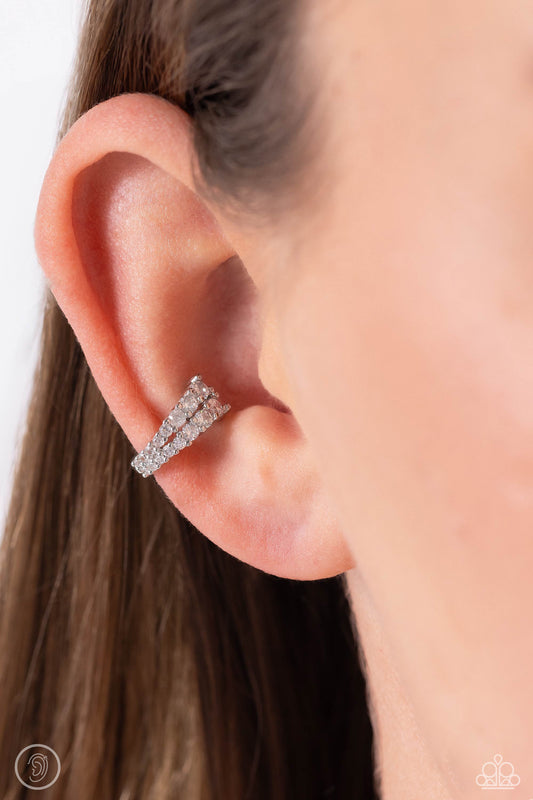 Pronged Parisian White Ear Cuff Earring - Paparazzi Accessories  Featuring a two-pronged fitting, white rhinestones with a light iridescent sheen gradually decrease in size to create a blinding, adjustable, one-size-fits-all cuff.  Sold as one pair of cuff earrings.  P5PO-CFWT-389XX
