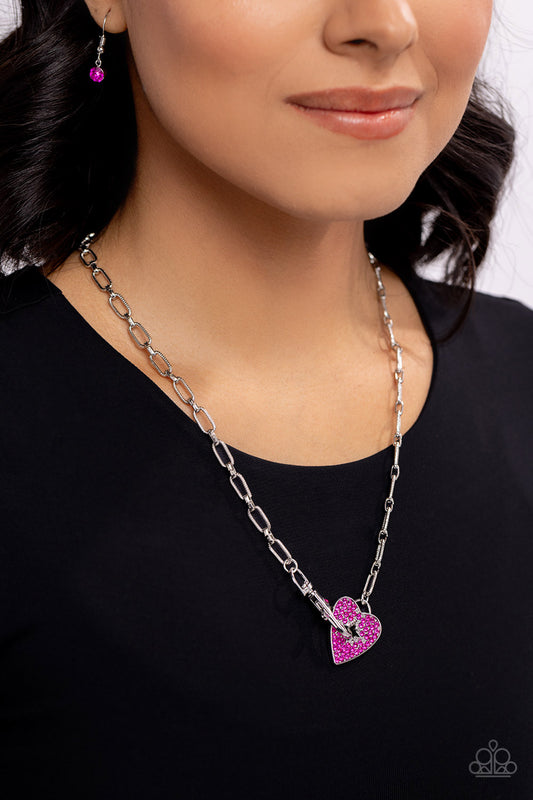 Radical Romance Pink Heart Necklace - Paparazzi Accessories  Featuring a subtly studded finish, a silver paperclip chain leads the eye down to a fuchsia rhinestone-encrusted heart. A fuchsia rhinestone-embellished lobster clasp connects to the center of the heart display for a touch of handcrafted hardware, creating a radiant centerpiece. Features a clasp closure.  Sold as one individual necklace. Includes one pair of matching earrings.  Sku:  P2DA-PKXX-186XX