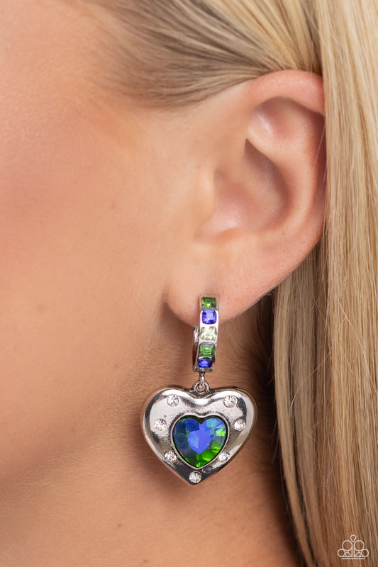 We Are Young Green Heart Hoop Earring - Paparazzi Accessories  Featuring a UV shimmer, a green/blue heart gem is pressed into an antiqued silver heart frame adorned in white rhinestones. The antiqued heart sways from the bottom of a thick silver hoop encrusted in square green, blue, and white gems resulting in a whimsical fashion. Earring attaches to a standard post fitting. Hoop measures approximately 3/4" in diameter. Due to its prismatic palette, color may vary.