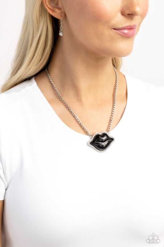 Lip Locked Black Necklace - Paparazzi Accessories  Featuring a glittery finish, an oversized black lip pendant swings from the bottom of a silver link chain below the collar for a romantic statement. White rhinestones border the charm for additional stunning detail. Features an adjustable clasp closure.  Sold as one individual necklace. Includes one pair of matching earrings.  P2ST-BKXX-224XX