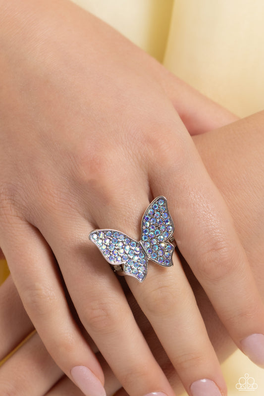 High Time Blue Butterfly Ring - Paparazzi Accessories  Featured atop airy silver bands, a silver butterfly encrusted with an explosion of blue iridescent rhinestones sparkles at the finger for an enchanting fashion. Features a stretchy band for a flexible fit. Due to its prismatic palette, color may vary.  Featured inside The Preview at Made for More!  Sold as one individual ring.  P4RE-BLXX-258RM