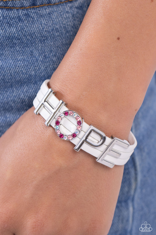 Hopeful Haute White Magnetic Bracelet - Paparazzi Accessories  Threaded along layers of white leather strands, glistening silver letters form the word "HOPE" with the "O" embossed in various shades of pink and pink iridescent rhinestones for a dazzling statement. Features a magnetic closure. Due to its prismatic palette, color may vary.  Sold as one individual bracelet.  SKU: P9SE-WTXX-262XX
