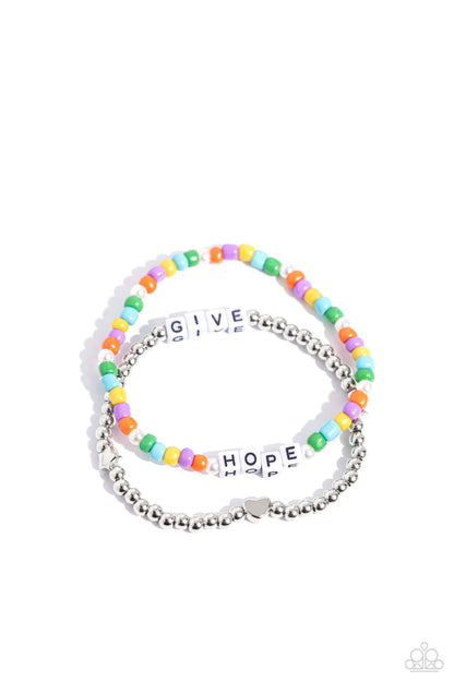 Giving Hope Multi Inspirational Stretch Bracelet - Paparazzi Accessories  Threaded along stretchy bands around the wrist, a strand of silver beads with a silver heart bead combines with a multicolored strand of seed beads and glossy white pearls to create a stunning pop of color. White cube beads are infused on each strand, spelling out the phrase "GIVE HOPE" between them, creating inspirational layers.  Sold as one set of two bracelets.  Sku:  P9WD-MTXX-060XX