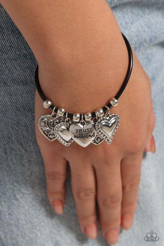 Totally Trusting Black Clasp Bracelet - Paparazzi Accessories  Infused with classic silver beads, an inspirational collection of silver heart charms dangle from the wrist along a black cord. Some hearts are encrusted with silver filigree and studs while one heart features the phrase "Trust in the Lord" topping off the charming look with dazzling detail. Features an adjustable clasp closure.  Sold as one individual bracelet.  New Kit Sku:  P9WD-BKXX-163XX