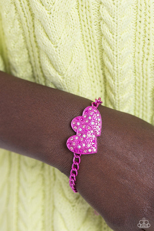 Lovestruck Lineup Pink Heart Bracelet - Paparazzi Accessories. Dipped in an electric pink hue, a strand of bulky chain gives way to two heart frames around the wrist. Dotted with tactile electric pink studs, the interlocked heart frames feature various pink and iridescent rhinestones for a timeless finish. Features an adjustable clasp closure. Sold as one individual bracelet. Get The Complete Look! Necklace: "Low-Key Lovestruck - Pink" (sold separately)