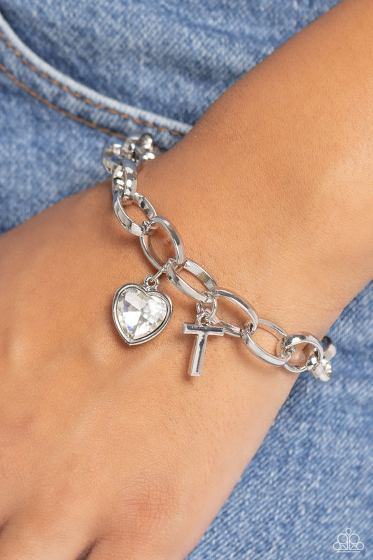 Guess Now Its INITIAL White "T" Bracelet - Paparazzi Accessories  A simple collection of silver charms — including a white rhinestone heart pressed in a silver frame and a sleek letter "T" — dance from a chunky silver chain around the wrist, creating a sentimental fringe. Features an adjustable clasp closure.  Sold as one individual bracelet.  New Kit Sku:  P9BA-WTXX-054XX