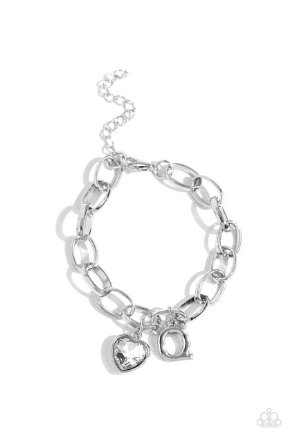 Guess Now Its INITIAL White "Q" Bracelet - Paparazzi Accessories  A simple collection of silver charms — including a white rhinestone heart pressed in a silver frame and a sleek letter "Q" — dance from a chunky silver chain around the wrist, creating a sentimental fringe. Features an adjustable clasp closure.  Sold as one individual bracelet.  New Kit Sku:  P9BA-WTXX-051XX