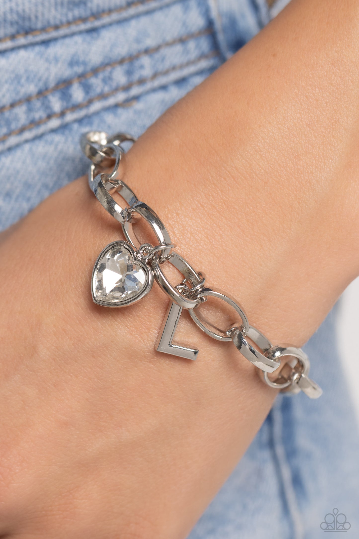 Guess Now Its INITIAL White "L" Bracelet - Paparazzi Accessories  A simple collection of silver charms — including a white rhinestone heart pressed in a silver frame and a sleek letter "L" — dance from a chunky silver chain around the wrist, creating a sentimental fringe. Features an adjustable clasp closure.  Sold as one individual bracelet.  New Kit Sku:  P9BA-WTXX-046XX