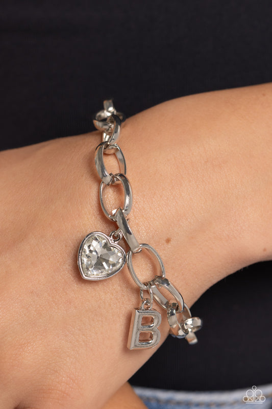 Guess Now Its INITIAL White "B" Bracelet - Paparazzi Accessories  A simple collection of silver charms — including a white rhinestone heart pressed in a silver frame and a sleek letter "B" — dance from a chunky silver chain around the wrist, creating a sentimental fringe. Features an adjustable clasp closure.  Sold as one individual bracelet.  New Kit Sku:  P9BA-WTXX-036XX
