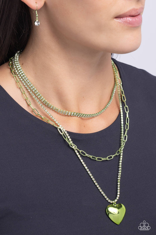 Caring Cascade Green Heart Necklace - Paparazzi Accessories  Featuring a green-painted hue, a trio of paperclip, rhinestone-encrusted box chain, and layered rhinestone-encrusted box chains coalesces down the neckline for a monochromatic masterpiece. Strung on the lowermost green box chain, a green heart pendant stands out and reflects light in every direction for a statement finish. Features an adjustable clasp closure.
