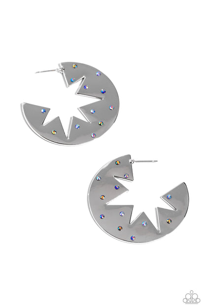 Starry Sensation Blue Star Hoop Earring - Paparazzi Accessories  Sporadically dotted with various blue and blue iridescent rhinestones, a three-dimensional star outline explodes from the center of a polished silver disc for an out-of-this-world centerpiece. Earring attaches to a standard post fitting. Hoop measures approximately 1 3/4" in diameter. Due to its prismatic palette, color may vary.  Sold as one pair of hoop earrings.  Sku:  P5HO-BLXX-061XX