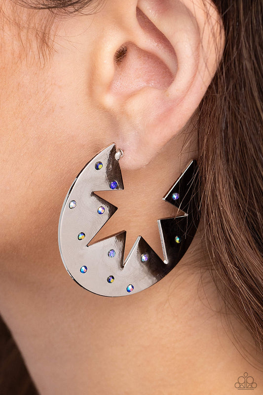 Starry Sensation Blue Star Hoop Earring - Paparazzi Accessories  Sporadically dotted with various blue and blue iridescent rhinestones, a three-dimensional star outline explodes from the center of a polished silver disc for an out-of-this-world centerpiece. Earring attaches to a standard post fitting. Hoop measures approximately 1 3/4" in diameter. Due to its prismatic palette, color may vary.  Sold as one pair of hoop earrings.  Sku:  P5HO-BLXX-061XX