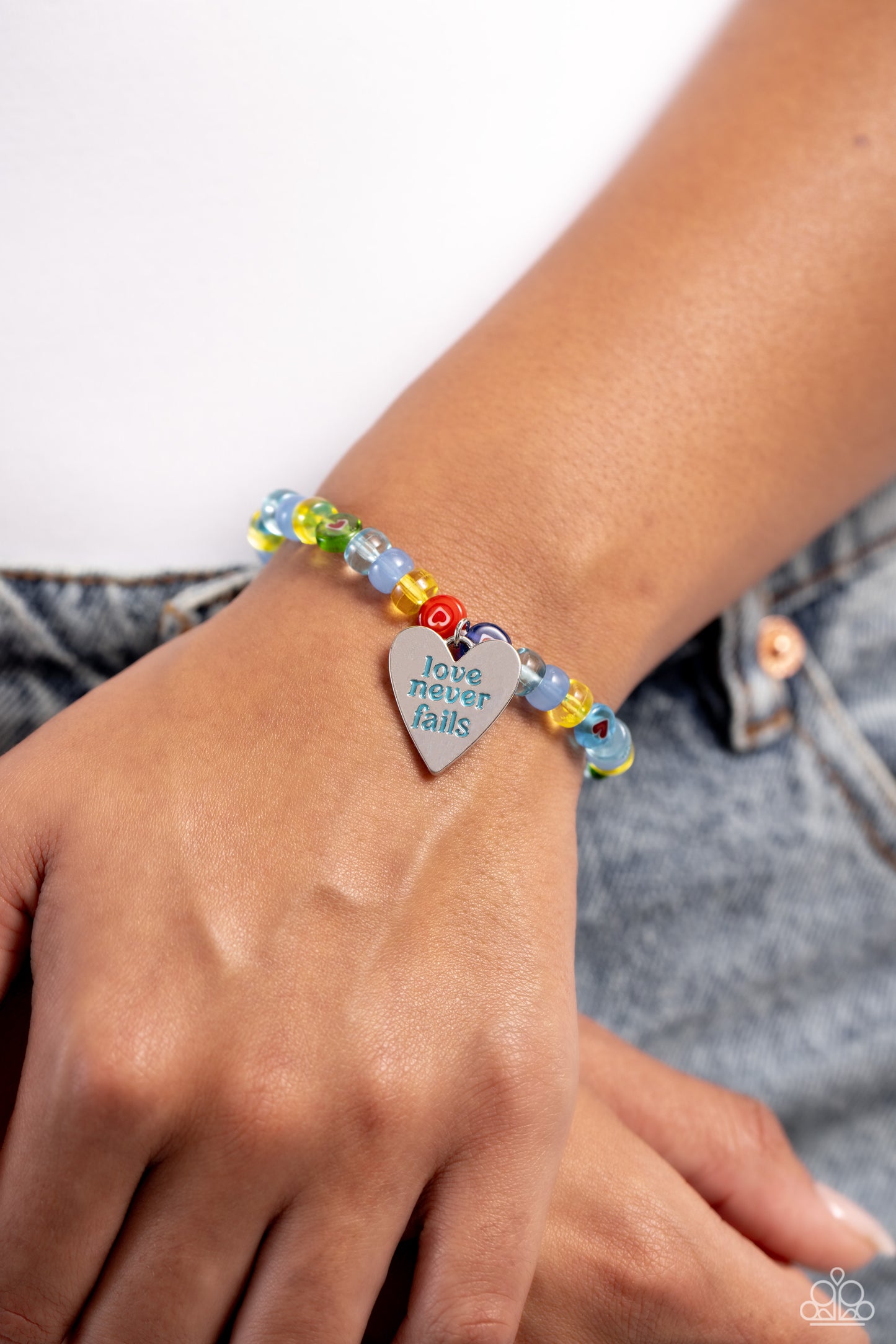 Unstoppable Love Multi Inspirational Bracelet - Paparazzi Accessories  Infused along an invisible string, multicolored glassy beads and beads with heart centers wrap around the wrist for a heartfelt statement. A silver heart with the stamped phrase "love never fails" in a blue font dangles below the multicolored design for an inspirational finish.  Sold as one individual bracelet.  P9WD-MTXX-065XX