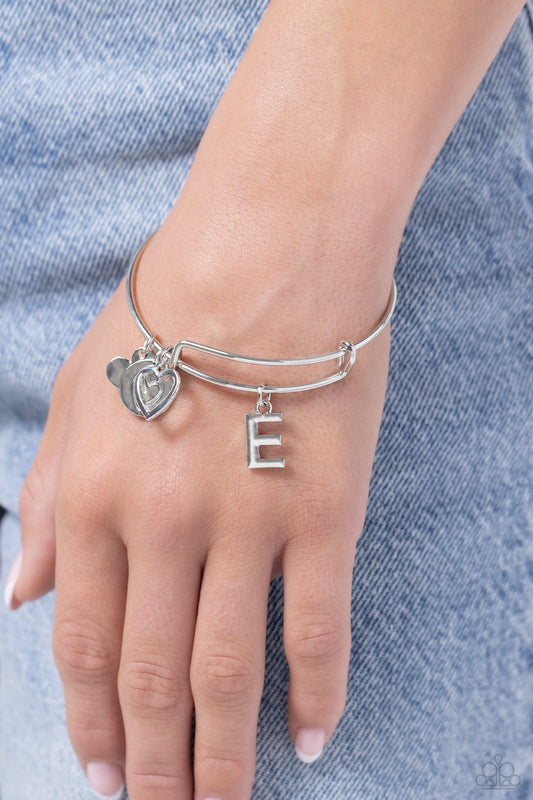 Making It INITIAL Silver "E" Bracelet - Paparazzi Accessories  Featuring shiny silver, airy, and stamped finishes, a mismatched collection of dainty heart charms, and the letter "E" glides along a silver bar fitting at the center of the wrist for a romantic, sentimental flair.  Sold as one individual bracelet.  SKU: P9BA-SVXX-189XX