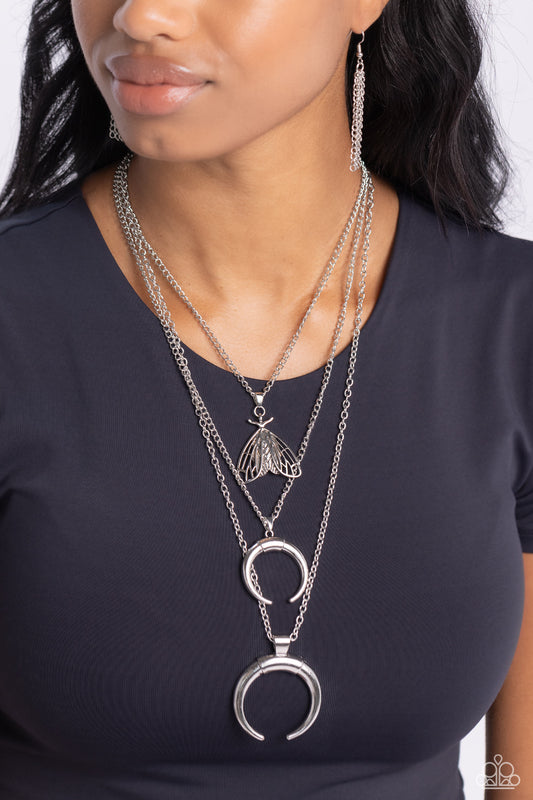 Moth Medley Silver Necklace - Paparazzi Accessories  Three strands of classic silver chain fall into tiered layers as they cascade down the chest. An oversized silver moth-detailed pendant and two half-circle silver pendants slide along each chain in a dizzying display, with thin bars of silver crowning the lowermost two pendants.  Sold as one individual necklace. Includes one pair of matching earrings.  Sku:  P2SE-SVXX-182XX