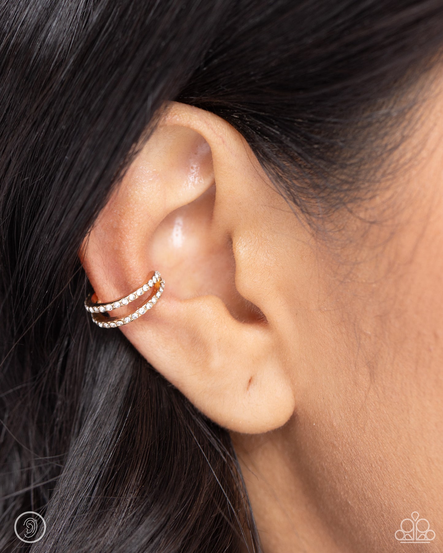Monochromatic Mystique Gold Ear Cuff - Paparazzi Accessories  Dusted in dainty white rhinestones, two thin gold bars crisscross around the ear for a dynamic statement. Features a smooth surface for sliding ability to desired position on the ear. Due to its structure, adjusting capability is limited.  Sold as one pair of cuff earrings.  SKU: P5PO-CFGD-280XX