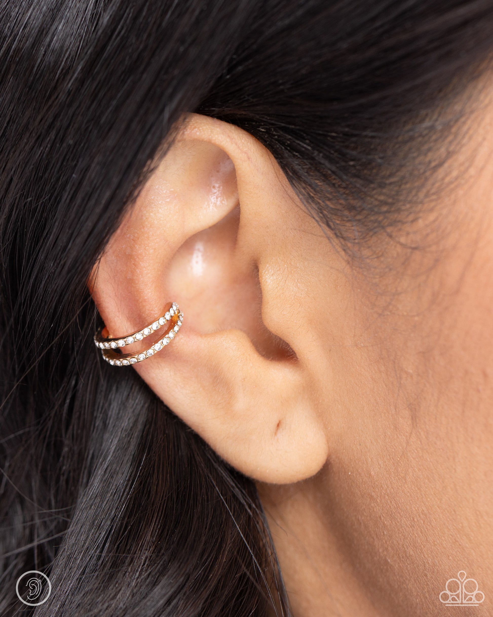 Monochromatic Mystique Gold Ear Cuff - Paparazzi Accessories  Dusted in dainty white rhinestones, two thin gold bars crisscross around the ear for a dynamic statement. Features a smooth surface for sliding ability to desired position on the ear. Due to its structure, adjusting capability is limited.  Sold as one pair of cuff earrings.  SKU: P5PO-CFGD-280XX