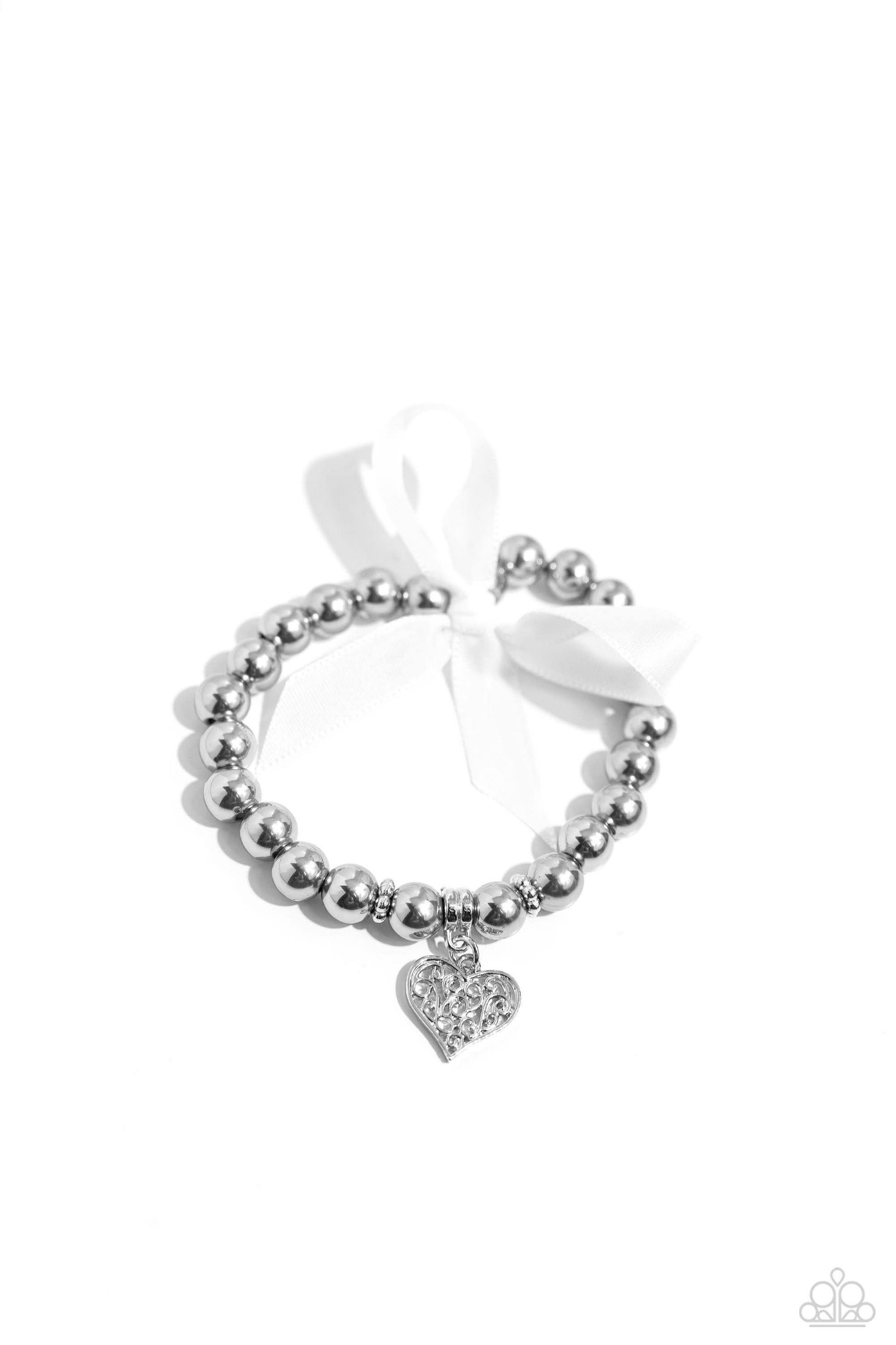 Prim and Pretty Silver Pearl Stretch Bracelet - Paparazzi Accessories  Gray iridescent pearls and silver beads are infused along an elastic stretchy band around the wrist. A white ribbon is tied in a bow on one end of the display, while a silver filigree heart charm cascades from the other end for a refined centerpiece.  Sold as one individual bracelet.  P9RE-SVXX-327XX