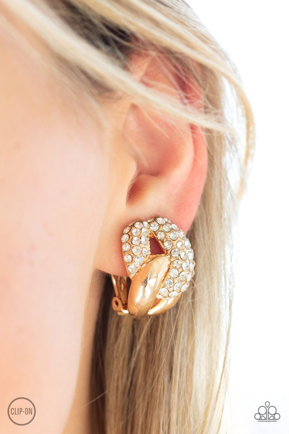 Definitely Date Night - Gold Item #E341 A white rhinestone encrusted link and glistening gold link connect into a bold frame for a refined look. Earring attaches to a standard clip-on fitting. All Paparazzi Accessories are lead free and nickel free!  Sold as one pair of clip-on earrings.