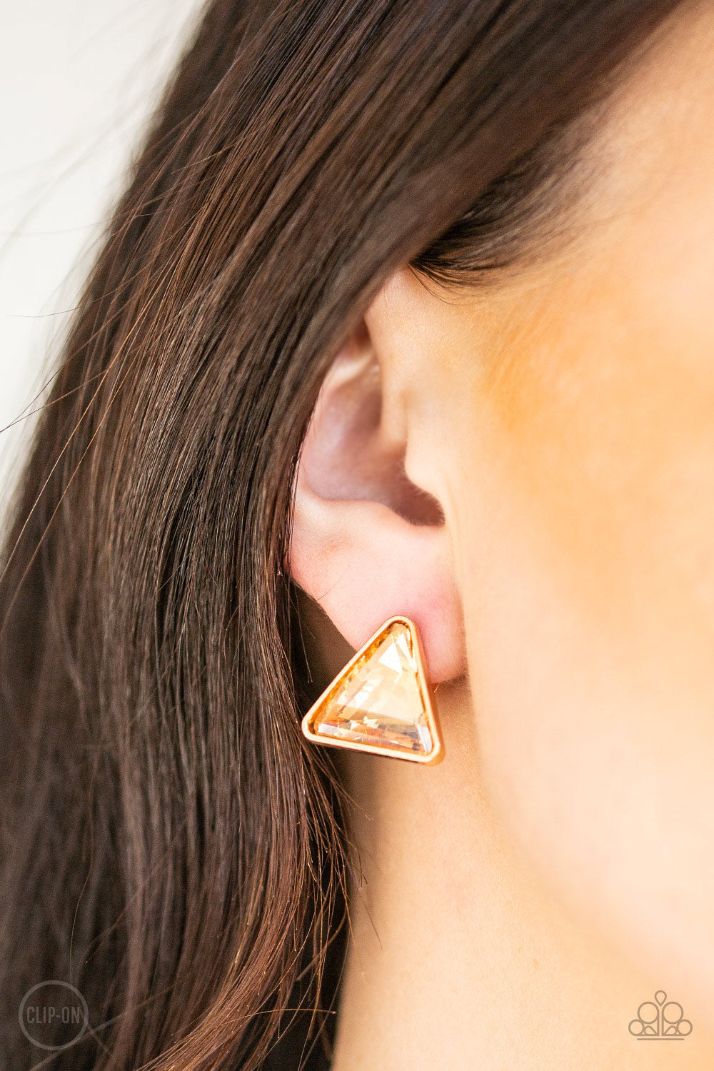 Timeless In Triangles - Gold Item #E156 Featuring a triangle-cut, a golden gem is pressed into a sleek gold frame for a timeless look. Earring attaches to a standard clip-on fitting. All Paparazzi Accessories are lead free and nickel free!  Sold as one pair of clip-on earrings.